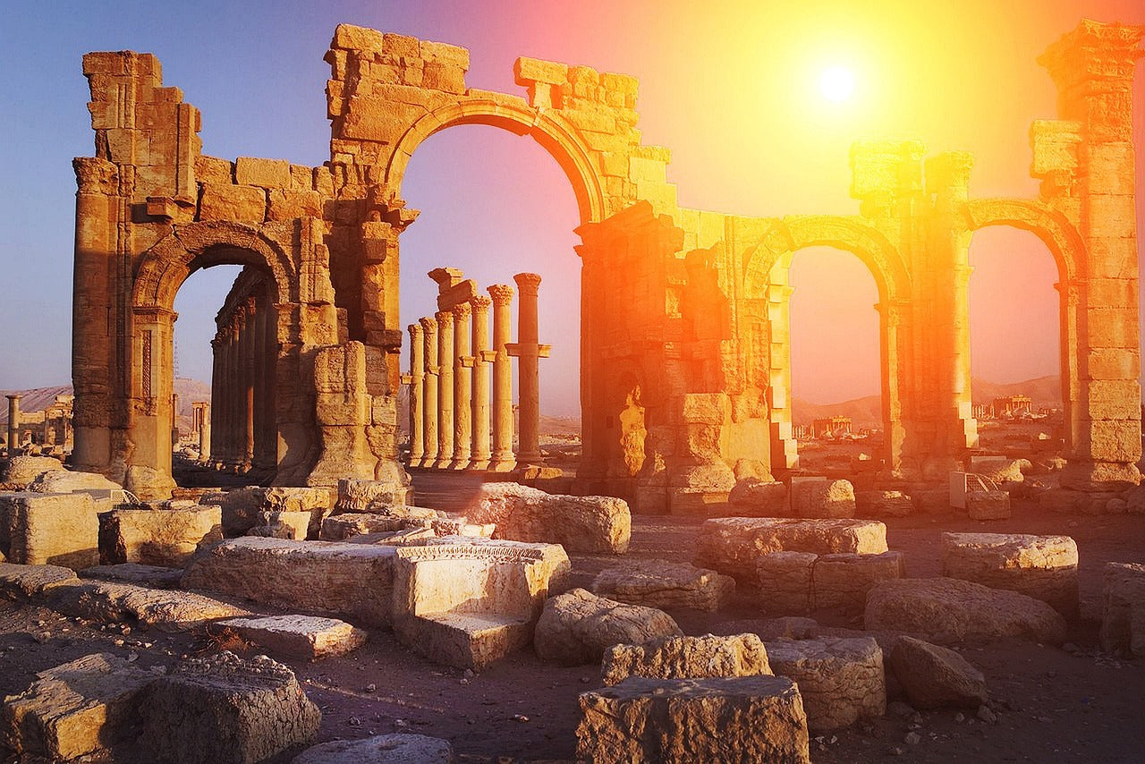 sun rising behind Greek ruins